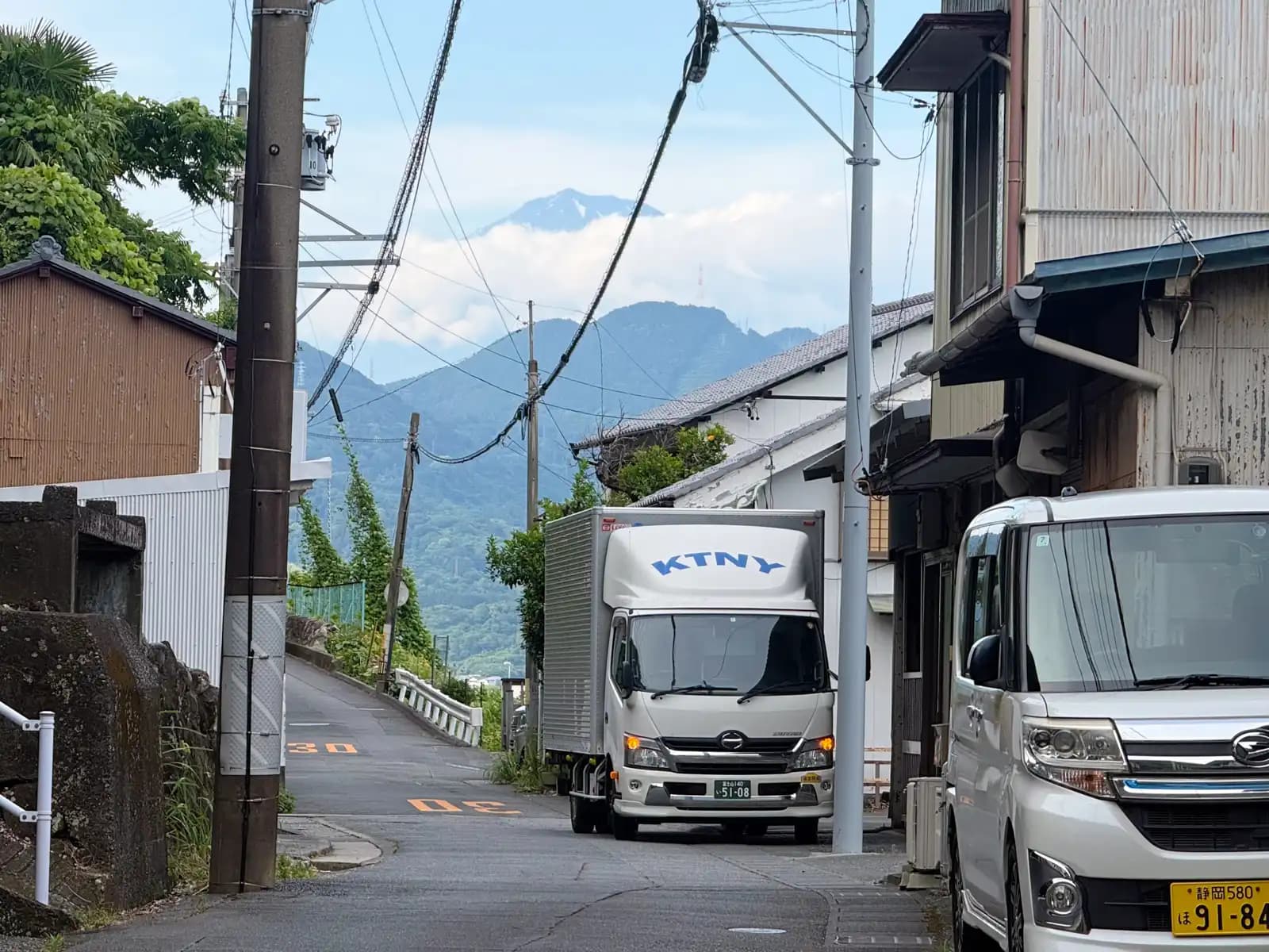 The lane below the pass. A delivery truck filling most of the road, and Fuji at the end of it.