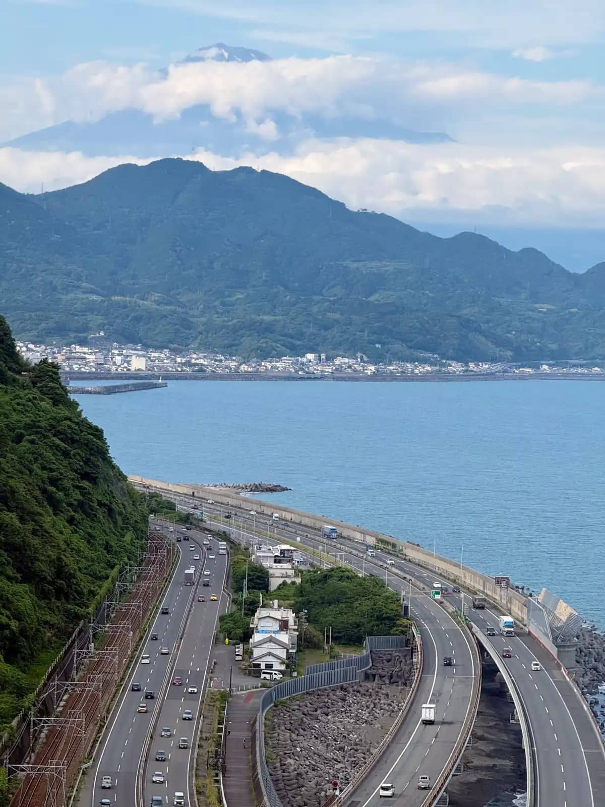 The view Satta Pass is known for: Fuji at the far end of Suruga Bay, with the road and railway squeezed in between the cliff and the water.