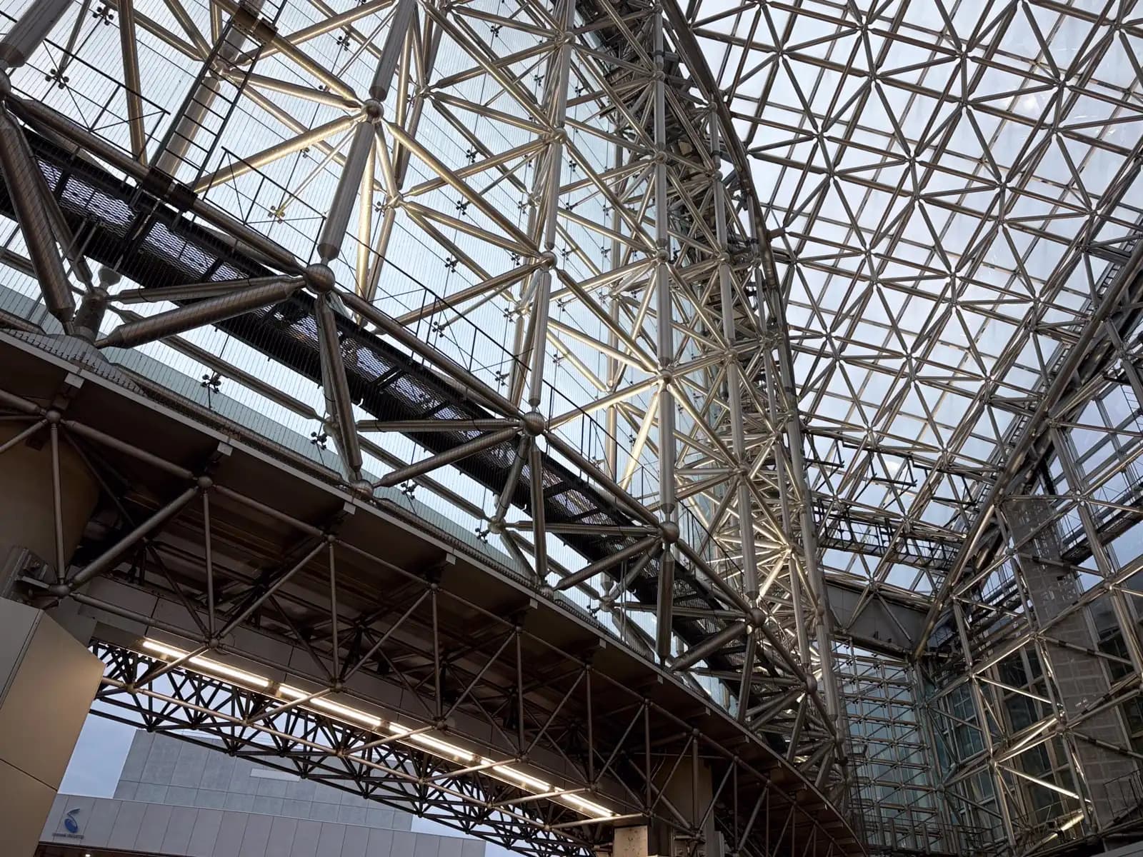 Looking up at the Motenashi Dome. The roof is made of glass panels held in a steel frame, with walkways for maintenance running along the top.