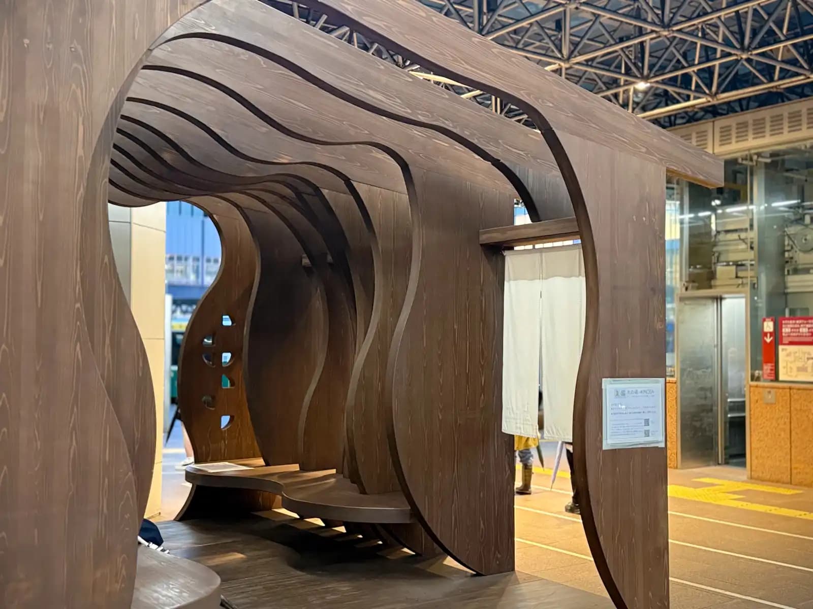 Inside the wooden seating structure. The curved wooden panels form a tunnel with benches built in.