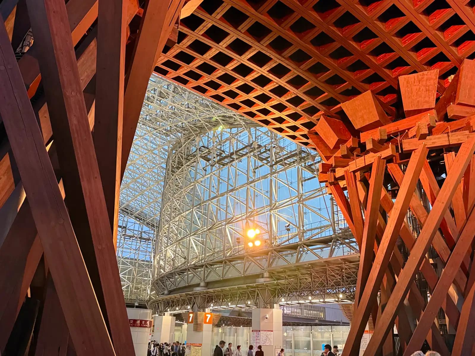 The Motenashi Dome seen between the two pillars of the Tsuzumi Gate in the evening. Bus stop 7 and the transportation information center are below.