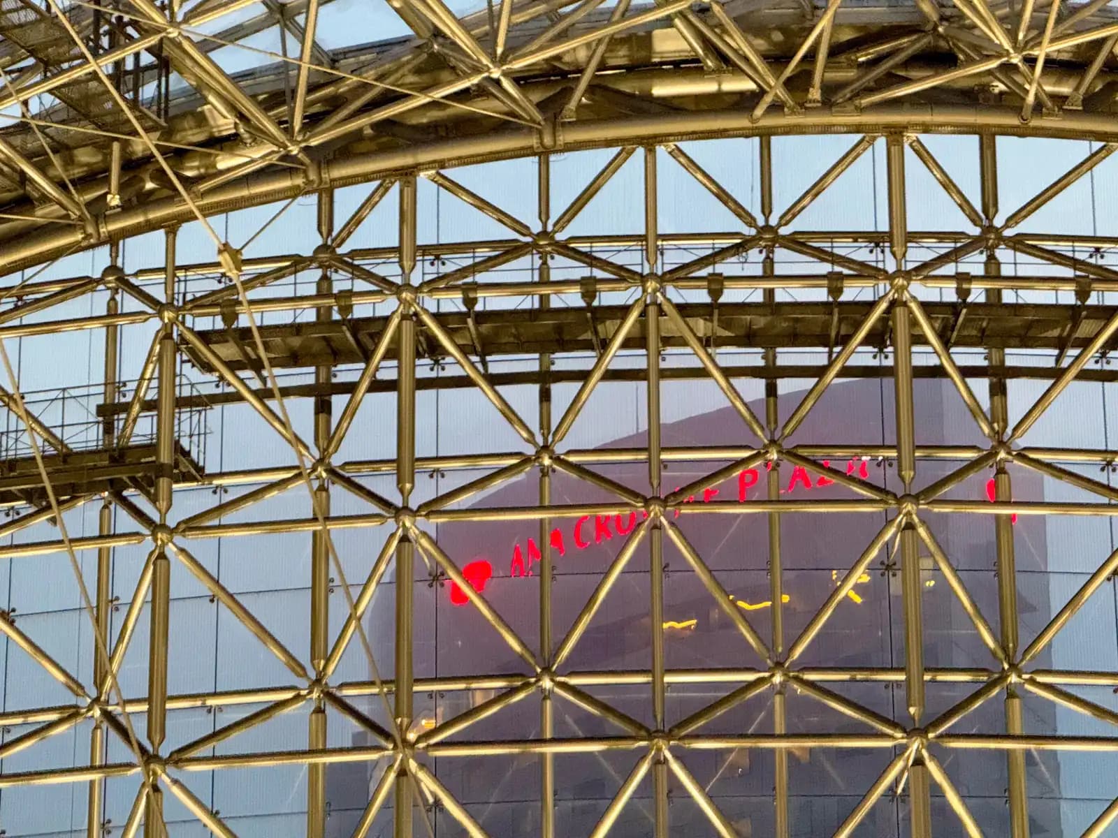The sign of the ANA Crowne Plaza hotel seen through the glass and steel frame of the Motenashi Dome.