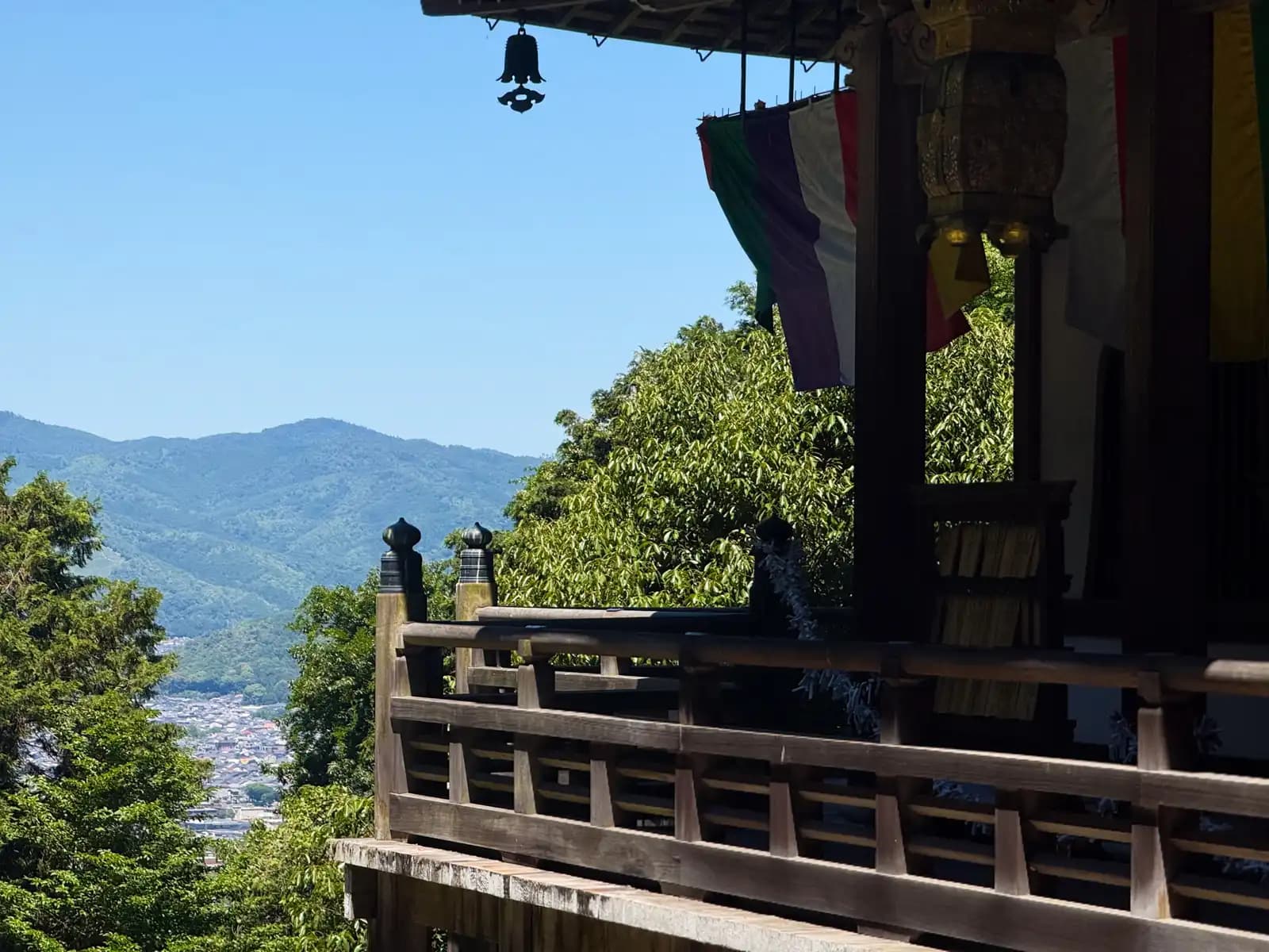 From the veranda a hanging bell frames the view out over the rooftops toward the western hills.