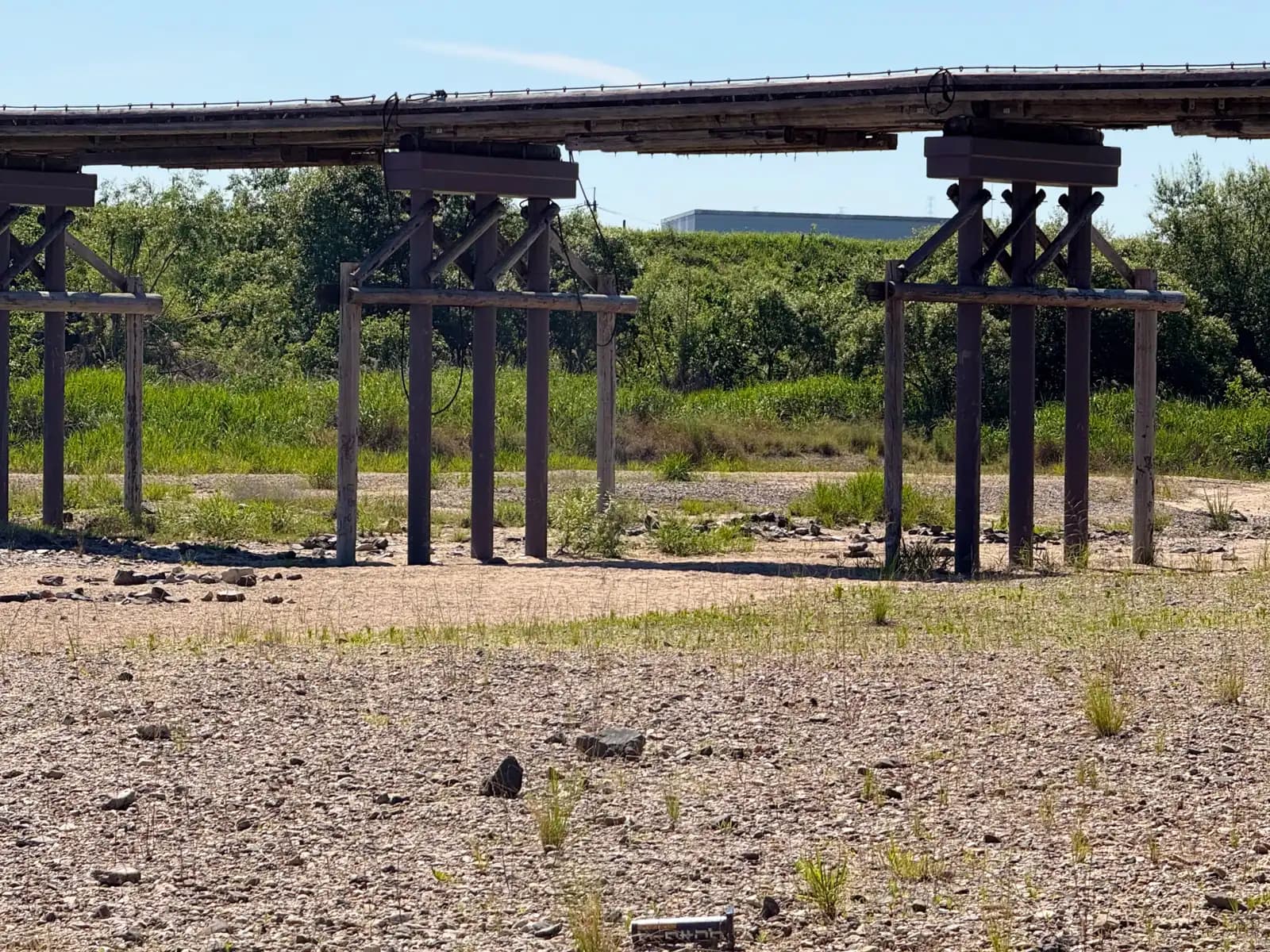The cross-braced pier bents seen from the stony riverbed, the deck floating above like a low ribbon.