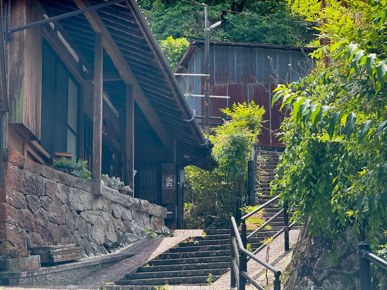 A wooden house on a stone base, with steps climbing the slope beside it.