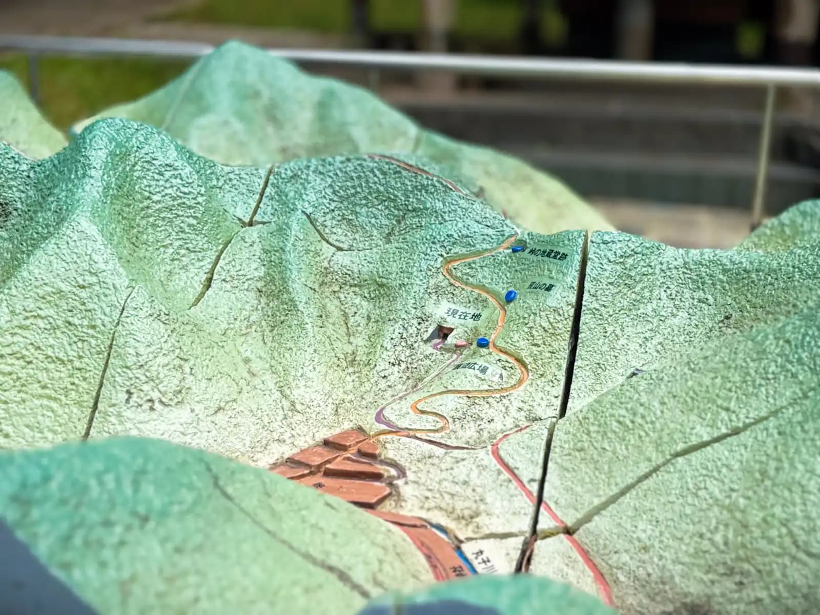 A scale model of the area, standing in the clearing in front of the tunnel. It shows the trail and the tunnel, with a pink marker for "you are here."