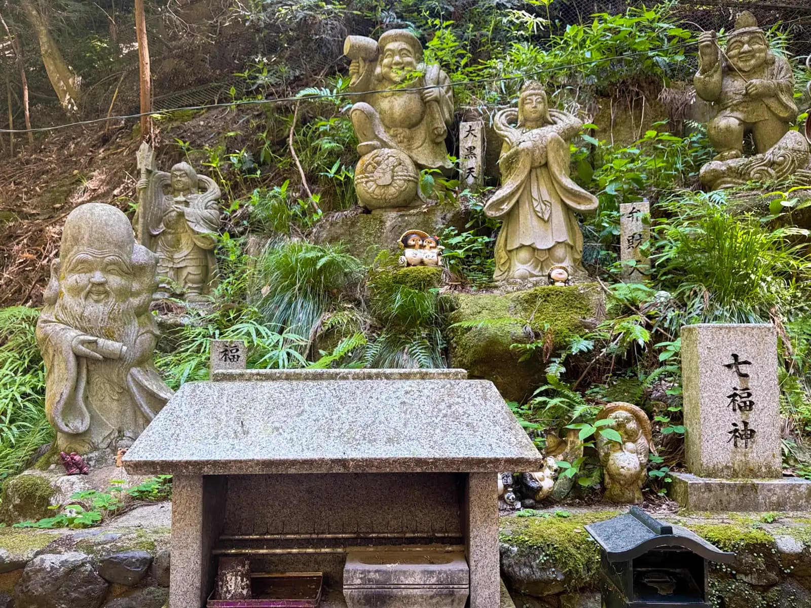 The Seven Lucky Gods carved in stone on the hillside: Daikokuten, Benzaiten and their companions.