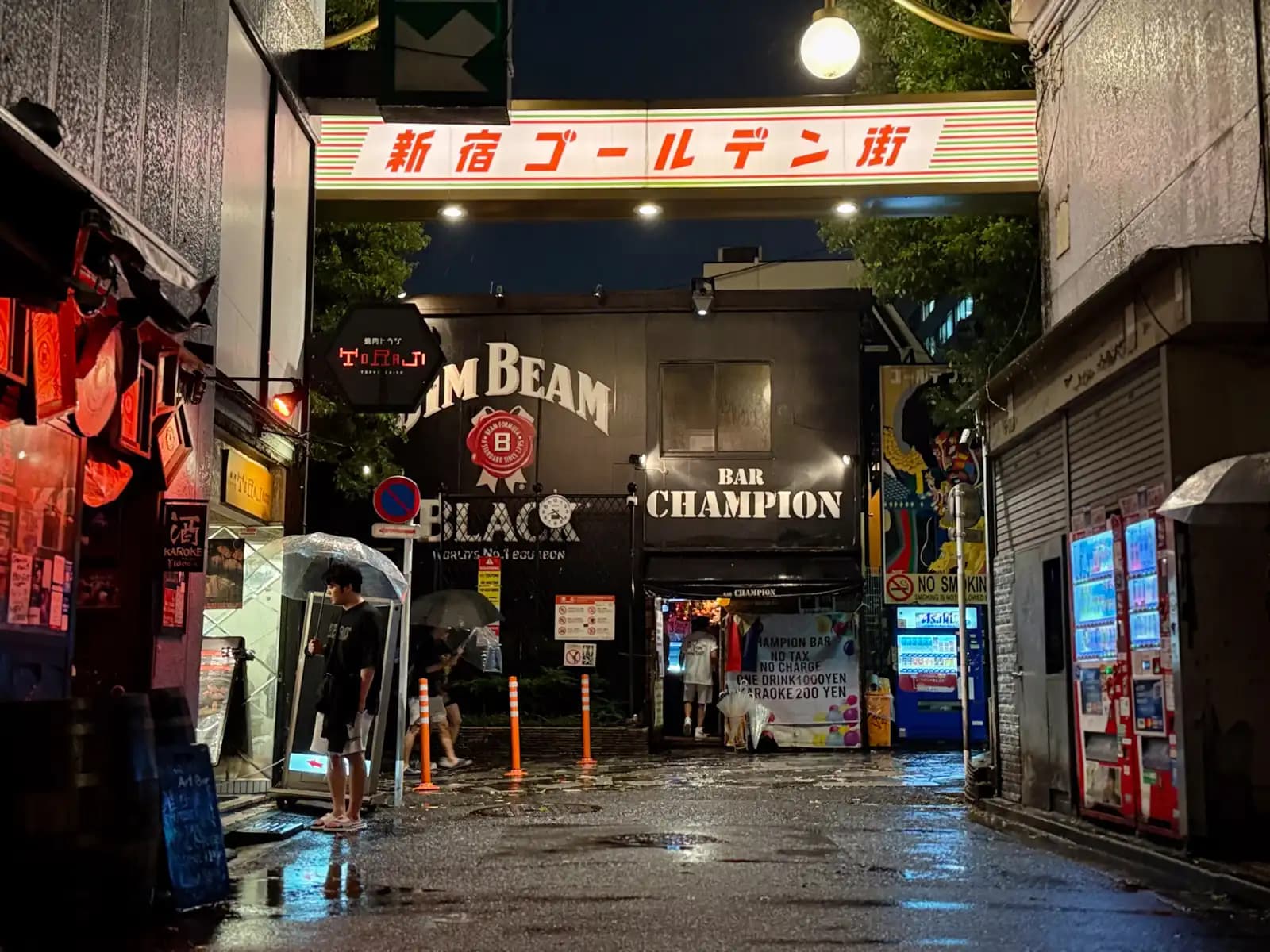 The Shinjuku Golden Gai sign over the entrance on a rainy night, with the popular Bar Champion straight ahead.