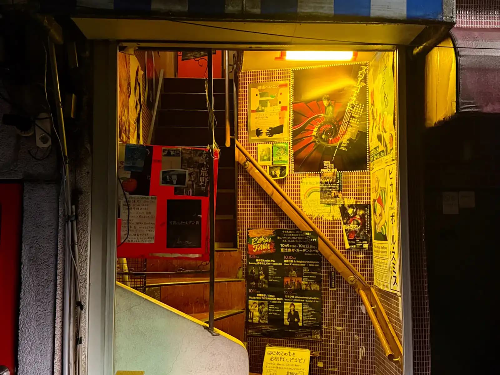 A lit-up stairwell covered in gig flyers and posters, including one for Picasso meets Paul Smith.