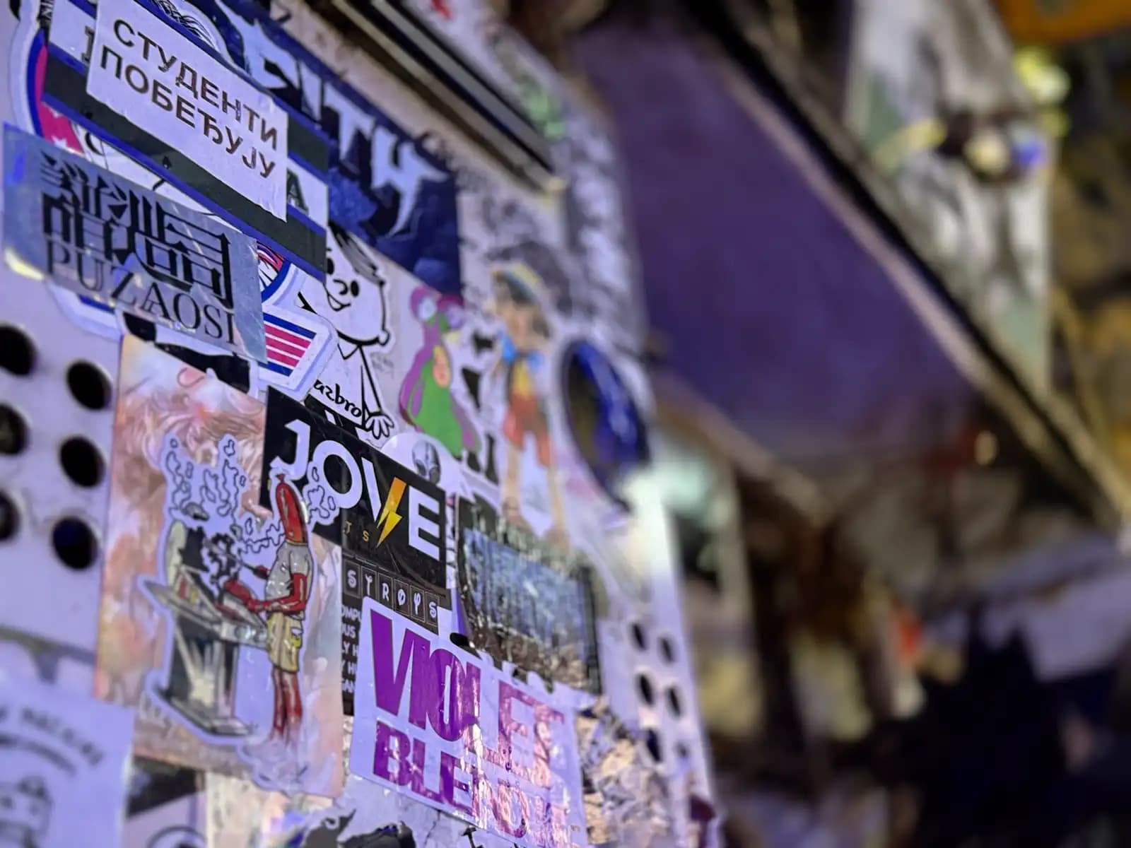 A wall packed with stickers, including one in Serbian that says "Students are winning."