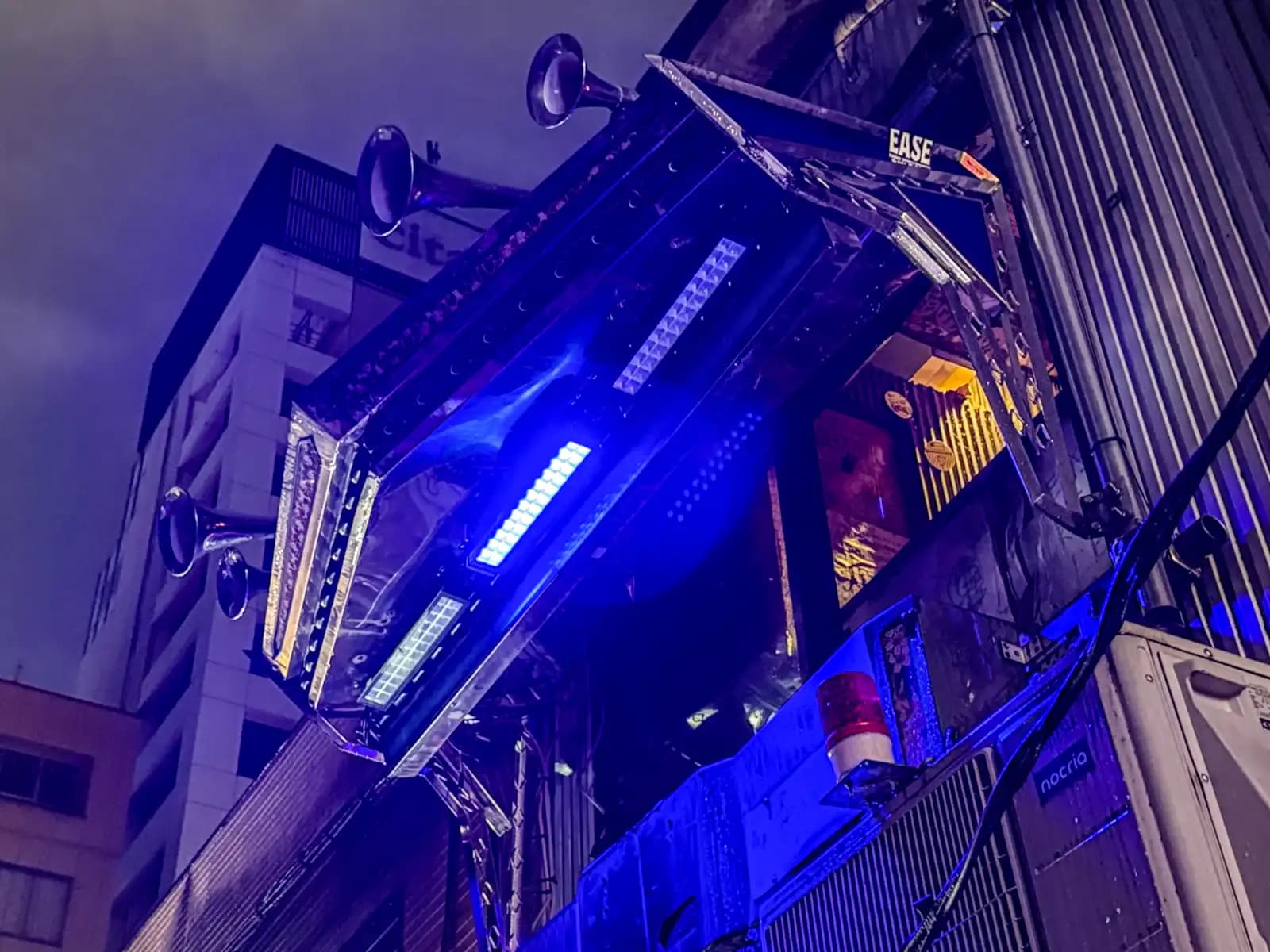 A bar front lit up in blue, with old horn speakers sticking out from the top.