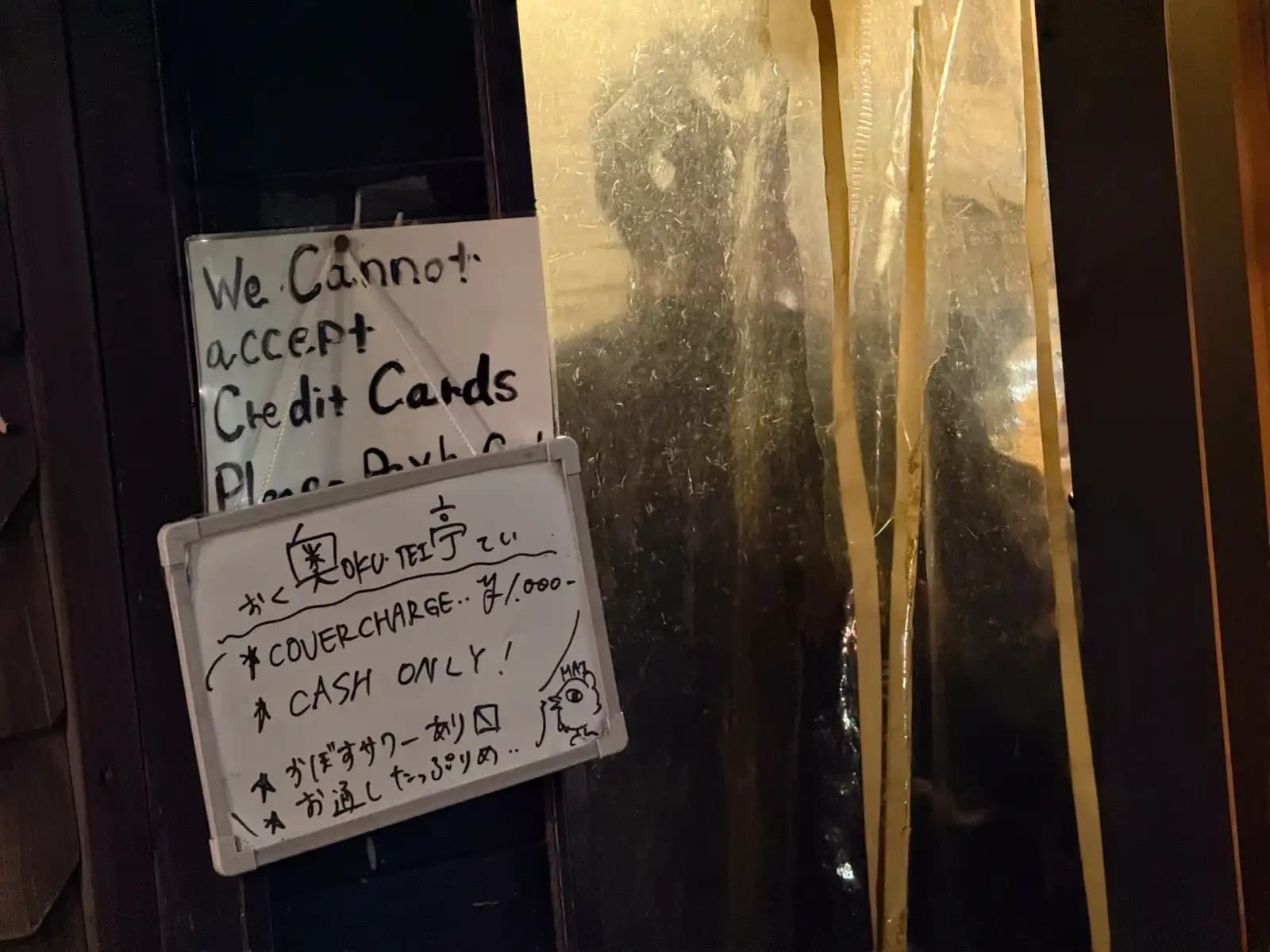 A handwritten whiteboard at Gyoro says the cover charge is 1,000 yen, cash only, next to a sign saying they can't take credit cards.