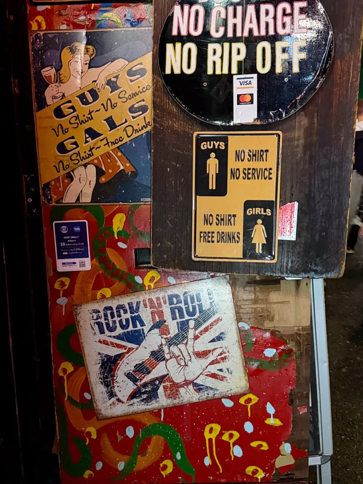 Tin signs by a bar door: "No Charge No Rip Off," "Guys No Shirt No Service, Girls No Shirt Free Drinks" and a Rock 'n' Roll plate.